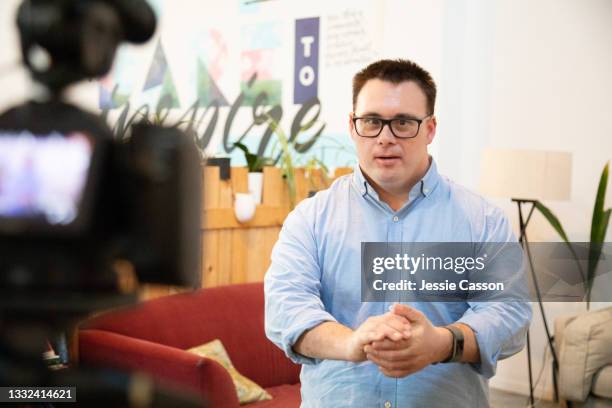 a man with down syndrome filming a vlog - media interview stockfoto's en -beelden
