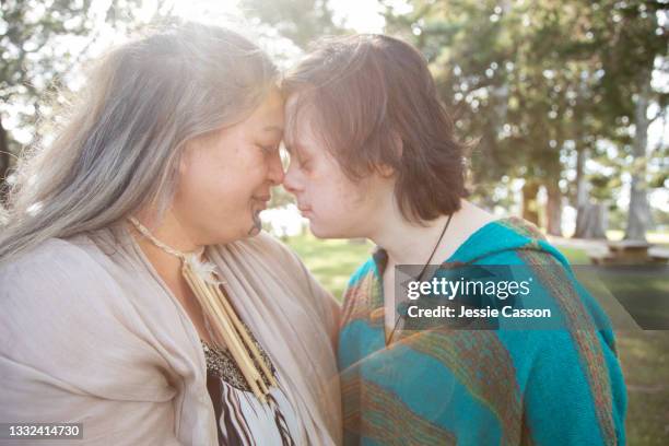 mother and son with down syndrome perform hongi in nature - maori family stock-fotos und bilder