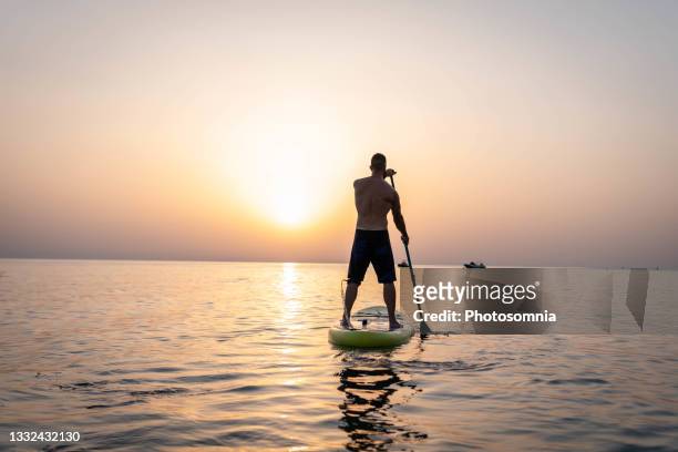 man paddleboarding at sunset - paddleboard stockfoto's en -beelden