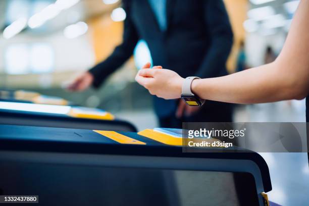 cropped shot of young asian woman checking in at subway station, making a quick and easy contactless payment for subway ticket via smartwatch. nfc technology, tap and go concept - nfc payment stock-fotos und bilder