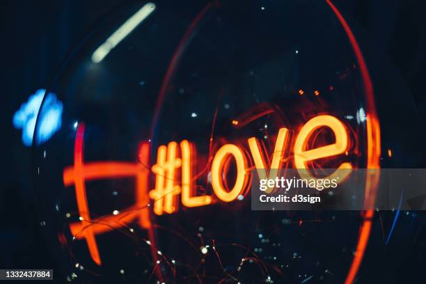 illuminated and glowing red "love" neon sign on wall at night - alphabet neon photos et images de collection