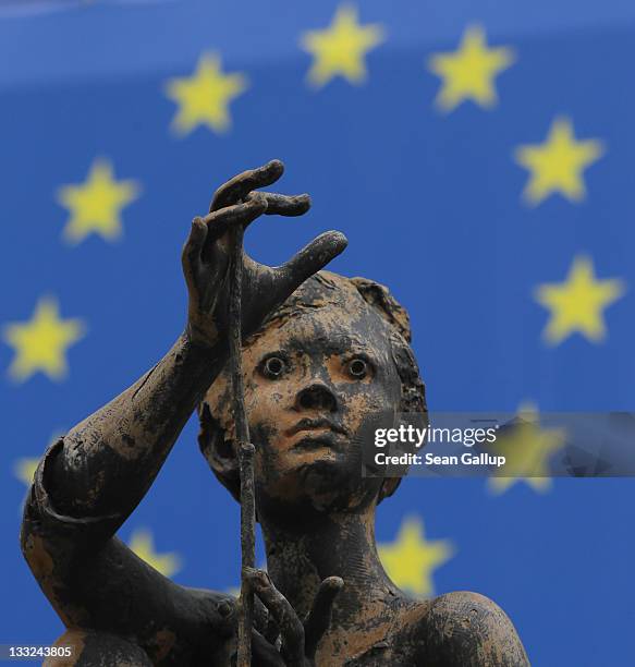 One of the sculptures of young girls by artist Rene Julien stands in front of a flag of the European Union at the Charlemagne building of the...