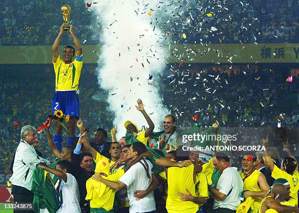 Brazil's team captain and defender Cafu hoists the World Cup trophy over the whole Brazilian team as confetti fall over the pitch during the award...
