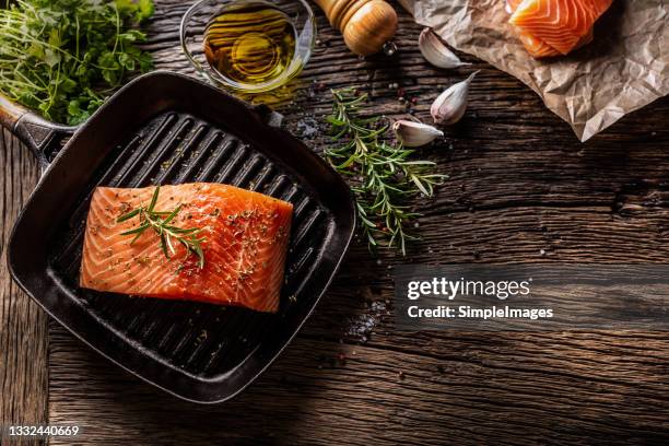 raw salmon steak in grill pan, salt, pepper, rosemary, olive oil and garlic on rustic oak table. - salmão imagens e fotografias de stock