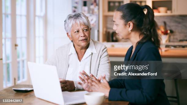 scatto di una donna anziana che usa un laptop durante un incontro con un consulente a casa - consigli foto e immagini stock
