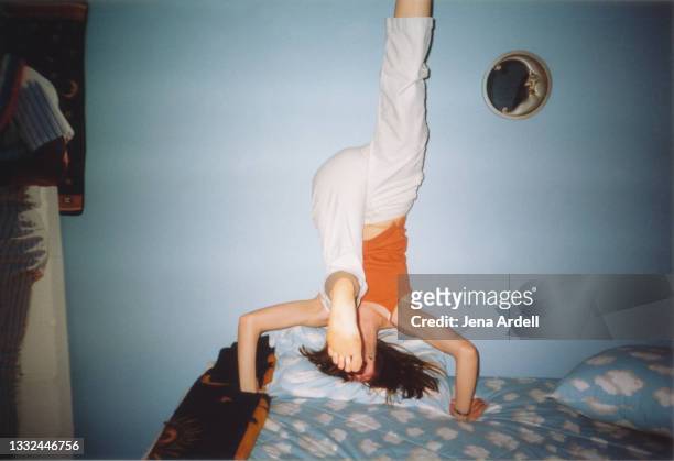 1990s teenager having fun, young girl doing headstand - levensecht stockfoto's en -beelden