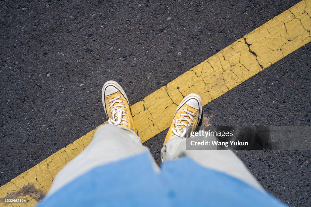 One foot on the yellow line of the road