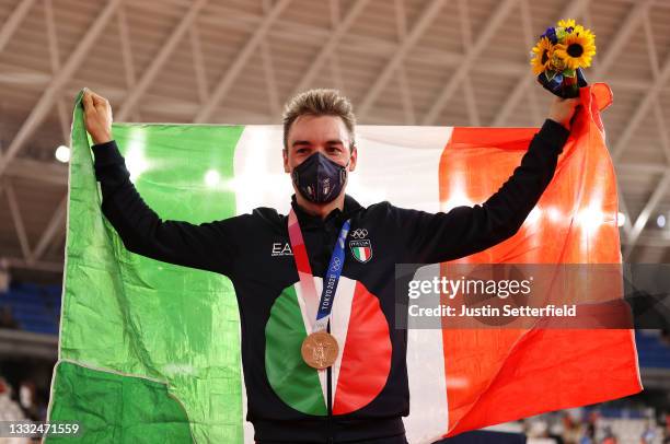 Bronze medalist Elia Viviani of Team Italy, pose on the podium while holding the flag of their country during the medal ceremony after the Men's...