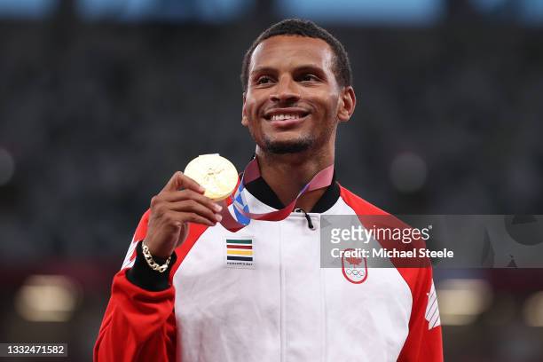 Gold medalist Andre De Grasse of Team Canada holds up his medal on the podium during the medal ceremony for the Men's 200 metres on day thirteen of...