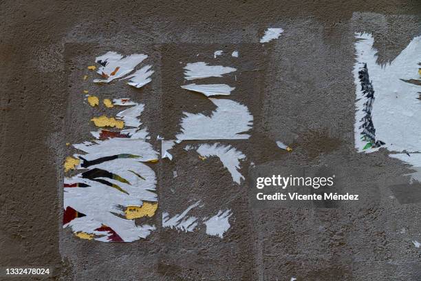 posters torn off on concrete wall - collant description physique photos et images de collection