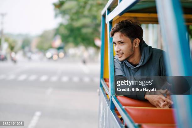 giovane guarda fuori con un autobus colorato - indonesian ethnicity foto e immagini stock