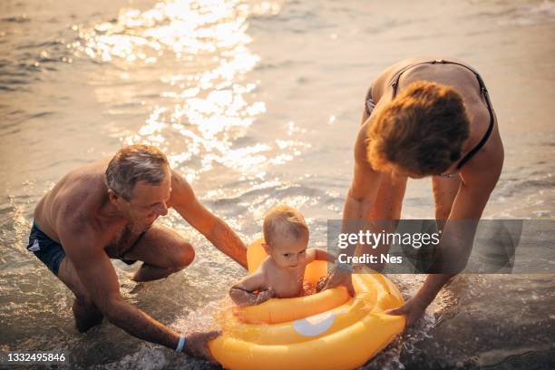 sommerurlaub am meer, großeltern mit enkel - babyschwimmen stock-fotos und bilder