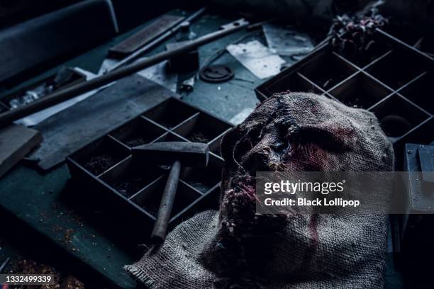 gruselige mördermaske auf dem tisch im dunkeln. - spooky stock-fotos und bilder