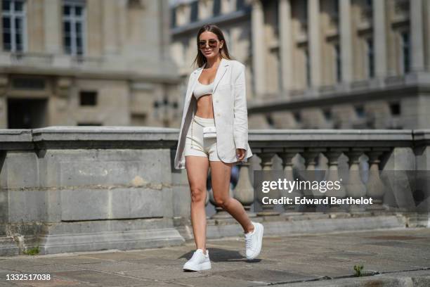 Diana Batovkina wears sunglasses, a beige V-neck / tank-top / ribbed bra underwear from Jacquemus, matching beige cyclist shorts from Jacquemus, a...