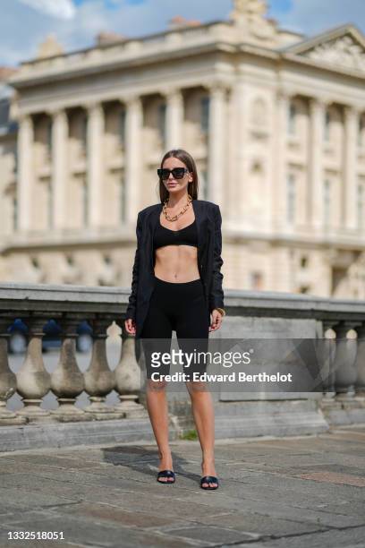 Diana Batovkina wears black sunglasses from Dior, a gold large chain necklace from Zara, a black V-neck / tank-top / ribbed bra underwear from...