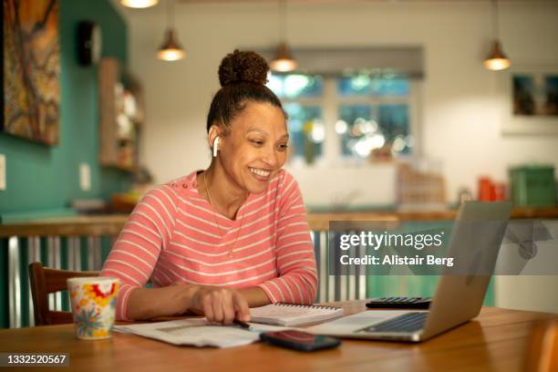 mixed race woman having a virtual meeting with her financial consultant from home - commode photos et images de collection