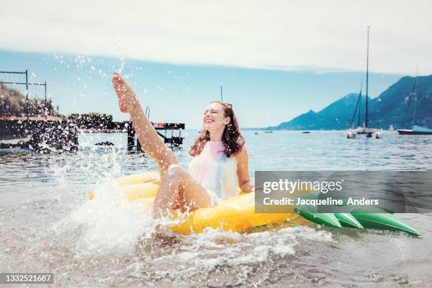 young woman on lake splashes water with feet on air mattress - hot women on boats ストックフォトと画像