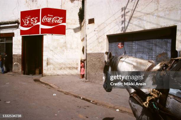 Horse pulling a wagon approaches a shop where Coca-Cola is advertised outside of Casablanca, Morocco in September 1978.