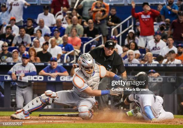 Miguel Rojas of the Miami Marlins avoids the tag sliding into home plate from Tomás Nido of the New York Mets in the eighth inning against the New...