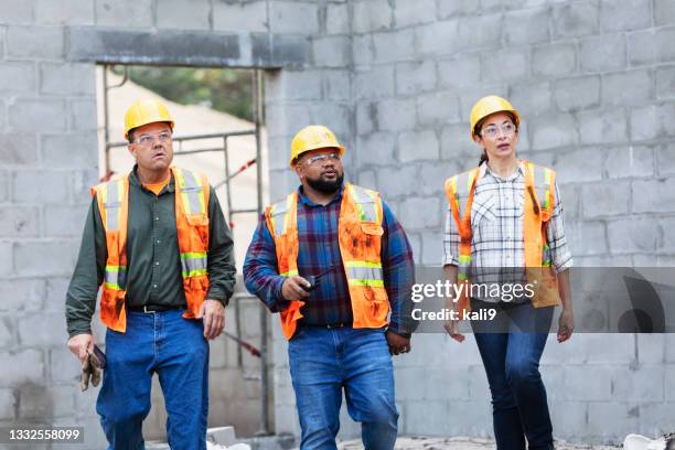 three multi-ethnic workers at building construction site - female with group of males stock pictures, royalty-free photos & images