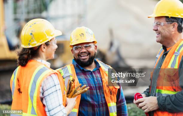 three multi-ethnic construction workers chatting - bouwvakker stockfoto's en -beelden