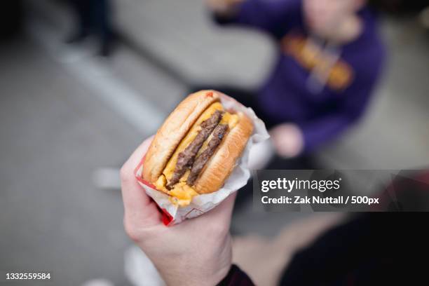 cropped hand of person holding burger,san francisco,california,united states,usa - unhealthy eating ストックフォトと画像