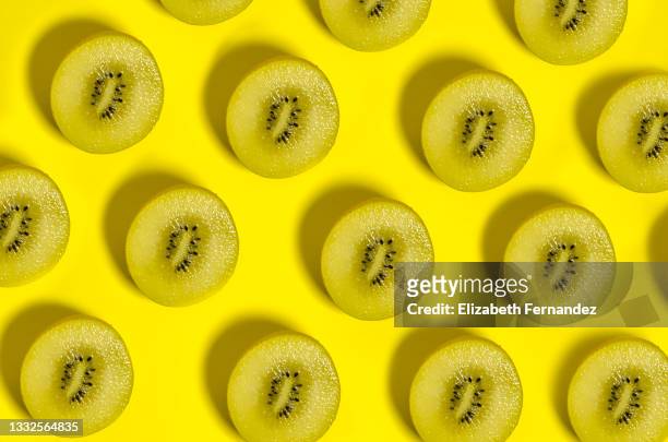kiwi sungold pattern on yellow background - kiwi fruit stock pictures, royalty-free photos & images