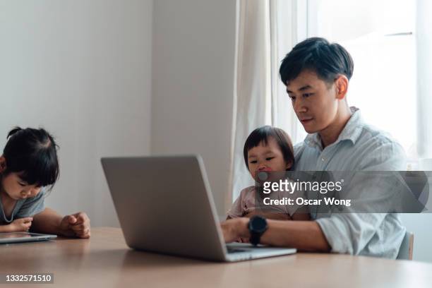 father multi-tasking - working at home and taking care of his daughters - hong kong community 個照片及圖片檔