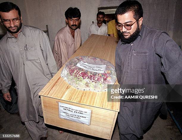 Volunteers from the Edhi Welfare Trust carry the coffin of US reporter Daniel Pearl from a mortuary in Karachi, 07 August 2002. An armed police...