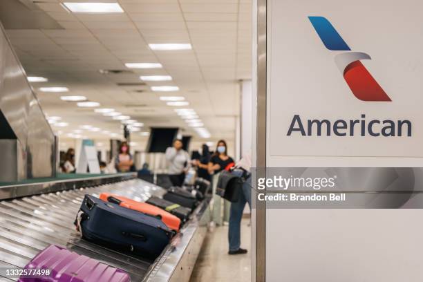People wait for their luggage at an American Airlines baggage claim at the George Bush Intercontinental Airport on August 05, 2021 in Houston, Texas....