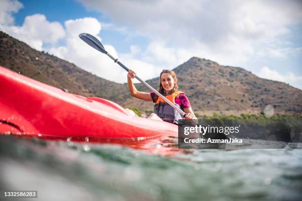 dynamic view of young female kayaker paddling past camera - zeekajakken stockfoto's en -beelden