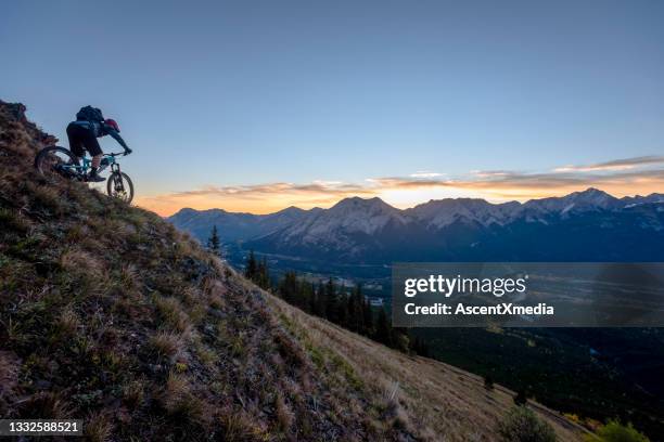 view of mountain biker descending mountain ridge - canmore stockfoto's en -beelden