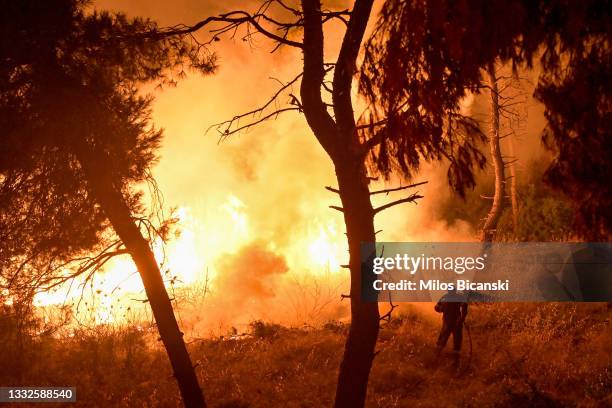 Firefighters try to put out a fire as flames spread over a highway during a wildfire on August 5 2021 in northern Athens , Greece. People were...