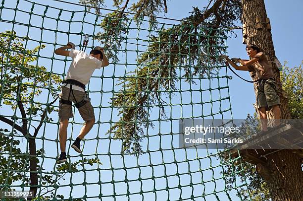boys on suspended net in adventure park - scala di corda foto e immagini stock