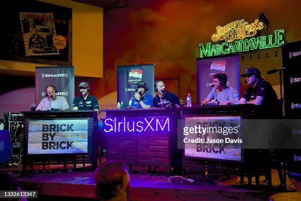 Jack Arute, Jack Harvey, Helio Castroneves, Tony Kanaan, Rinus Vaakay, and Conor Daly speak onstage as SiriusXM broadcasts from Margaritaville ahead...