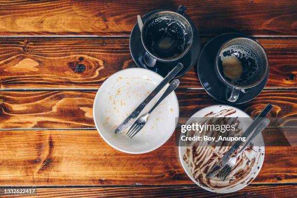 high angle view of finished food plate and empty cup of coffee on wooden table in restaurant. - messy table after party stock-fotos und bilder