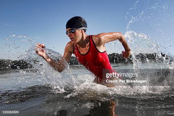 female triathlete running out of water - triathlon stock pictures, royalty-free photos & images