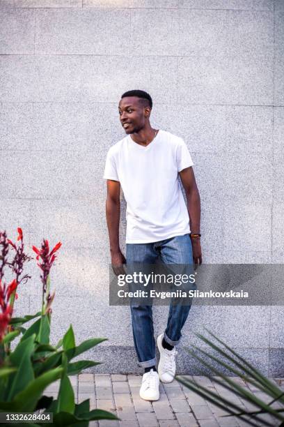 close-up portrait of smiling young african man against gray background. - jeans neri foto e immagini stock