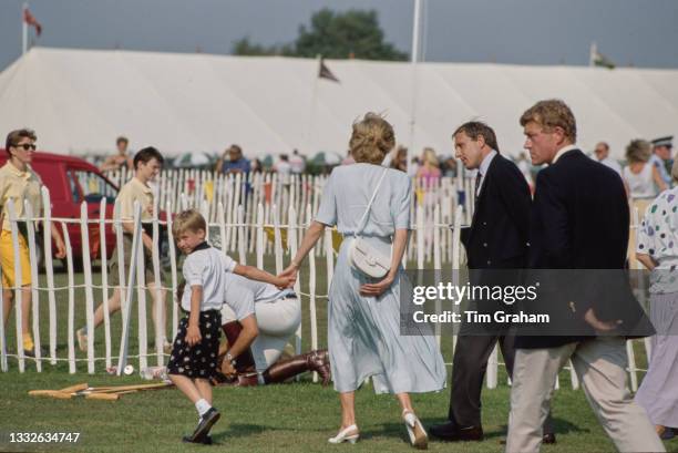 British Royal Diana, Princess of Wales , wearing a pale blue Catherine Walker dress, holds the hand of her son Prince William as they are escorted by...