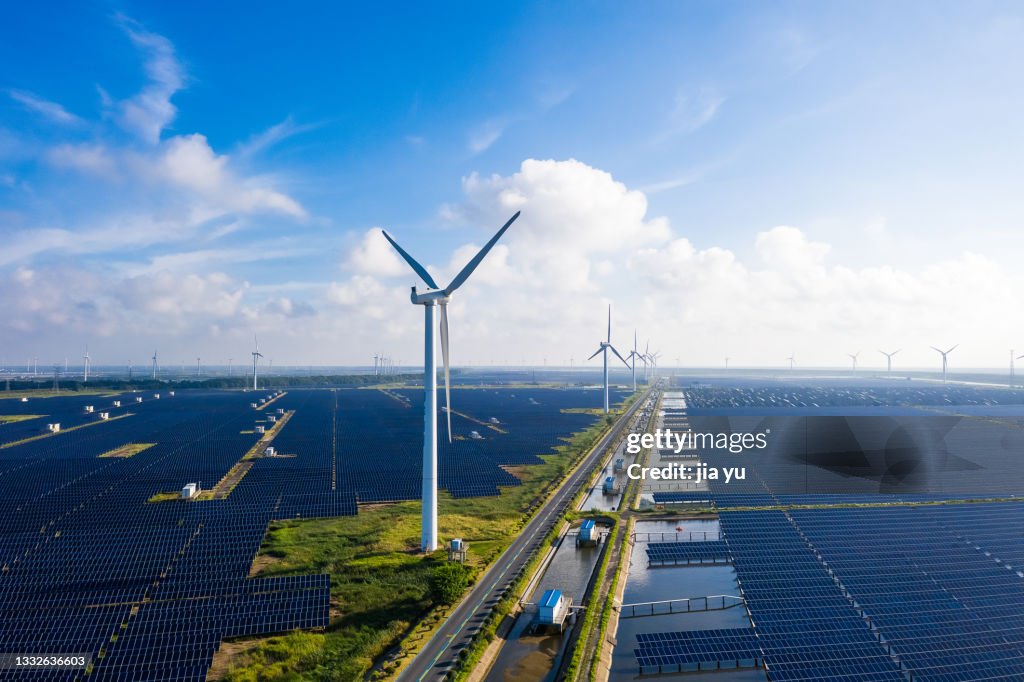 Solar power stations in plain areas, wind turbines in the distance. Yancheng City, Jiangsu Province, China.