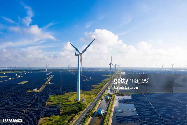 solar power stations in plain areas, wind turbines in the distance. yancheng city, jiangsu province, china. - light natural phenomenon foto e immagini stock