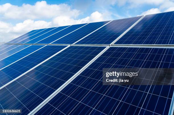 blue solar panels, distant wind turbines. yancheng city, jiangsu province, china. - solar panel city stock-fotos und bilder