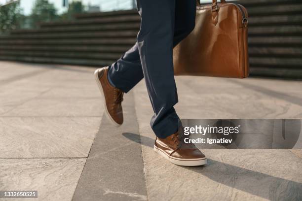 a man's legs in a blue pants, during the walk on a paved street - laptop bag stock pictures, royalty-free photos & images