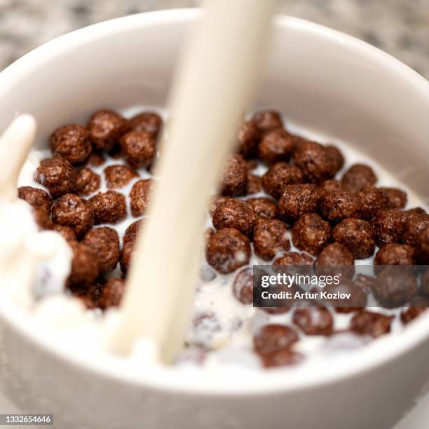 crispy chocolate balls with milk pouring in bowl. delicious breakfast. dairy and cereal products. close-up shot. soft focus - cereais de pequeno almoço imagens e fotografias de stock