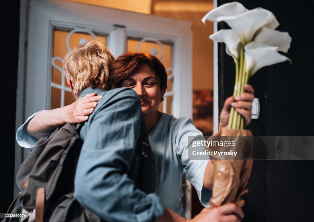 Young man hugging a senior woman at the door