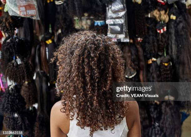 young african woman from behind with curly hair in a wig shop. - wig fotografías e imágenes de stock