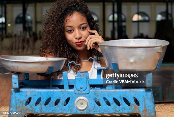 blue rusty weighing scales with a young african woman with curly hair behind it. - kilogram photos et images de collection