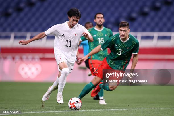 Kaoru Mitoma of Team Japan runs with the ball whilst under pressure from Cesar Montes of Team Mexico during the Men's Bronze Medal Match between...