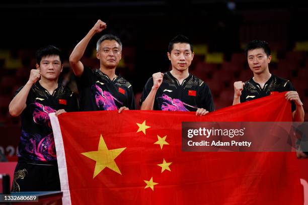 Fan Zhengdong of Team China, his coach Qiu Zhijian, teammates Xu Xin and Ma Long hold up their national flag after winning their Men's Team Gold...