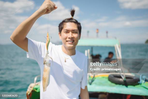 proud asian men holding a live squid fish from the sea with smiling face on the fishing boat in thailand asia - squid stock pictures, royalty-free photos & images